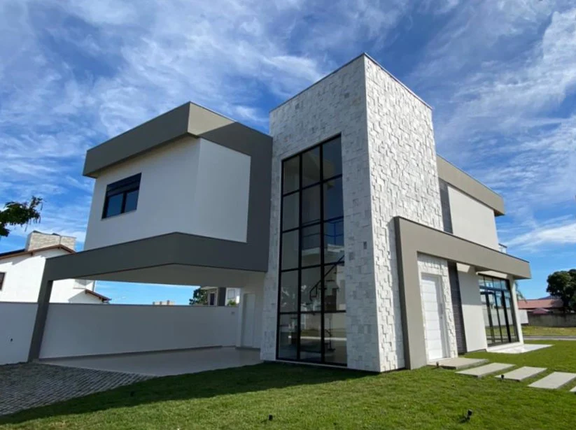 Foto da obra concluída em perspectiva, com o volume em pedra clara e as esquadrias escuras