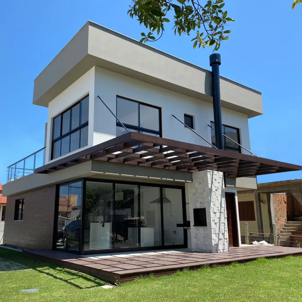 Foto da obra concluída em perspectiva posterior, mostrando as portas de correr de grande vão sob o pergolado