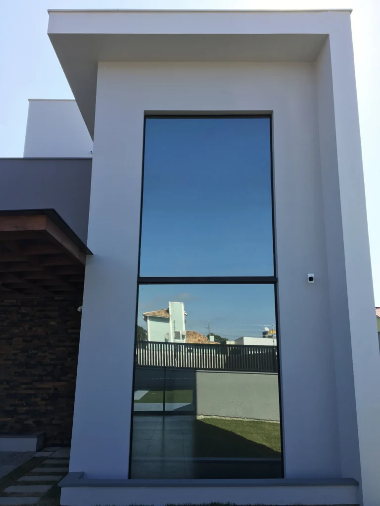 Foto da obra concluída, fachada frontal, com a esquadria de pé-direito duplo emoldurada pelo plano branco