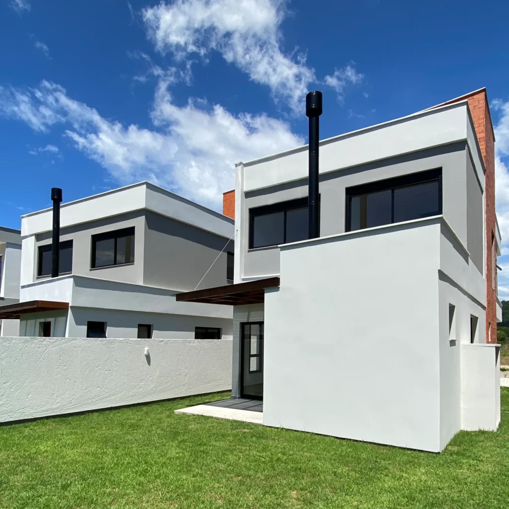 Foto da obra concluída em perspectiva posterior, com os volumes escalonados das duas casas